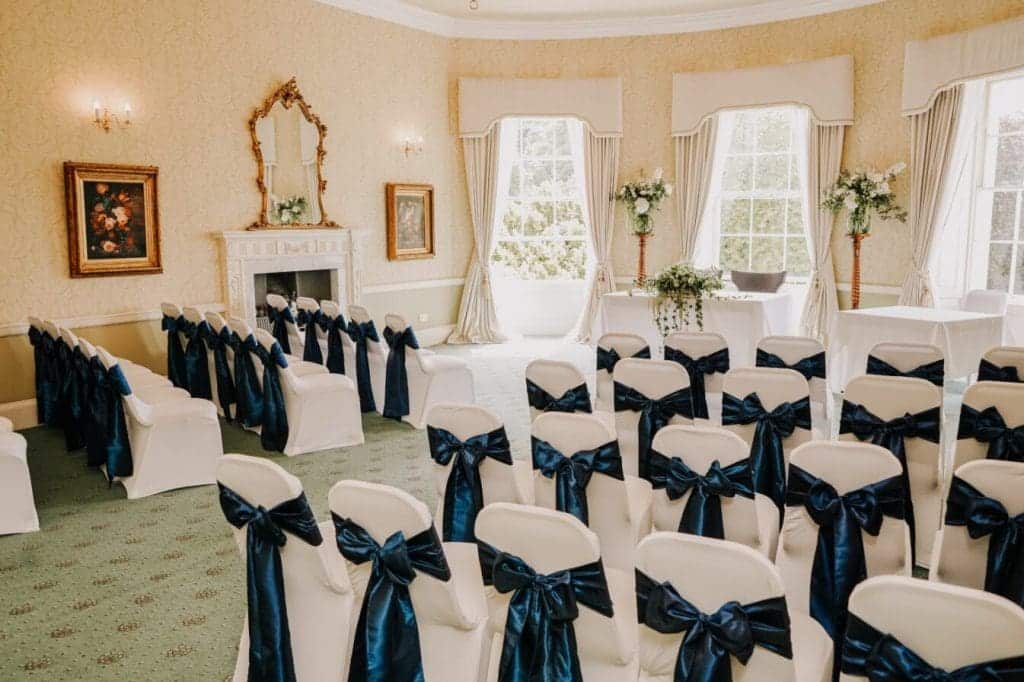 The de Lacey wedding ceremony room with white chair covers and blue sashes