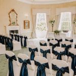 The de Lacey wedding ceremony room with white chair covers and blue sashes
